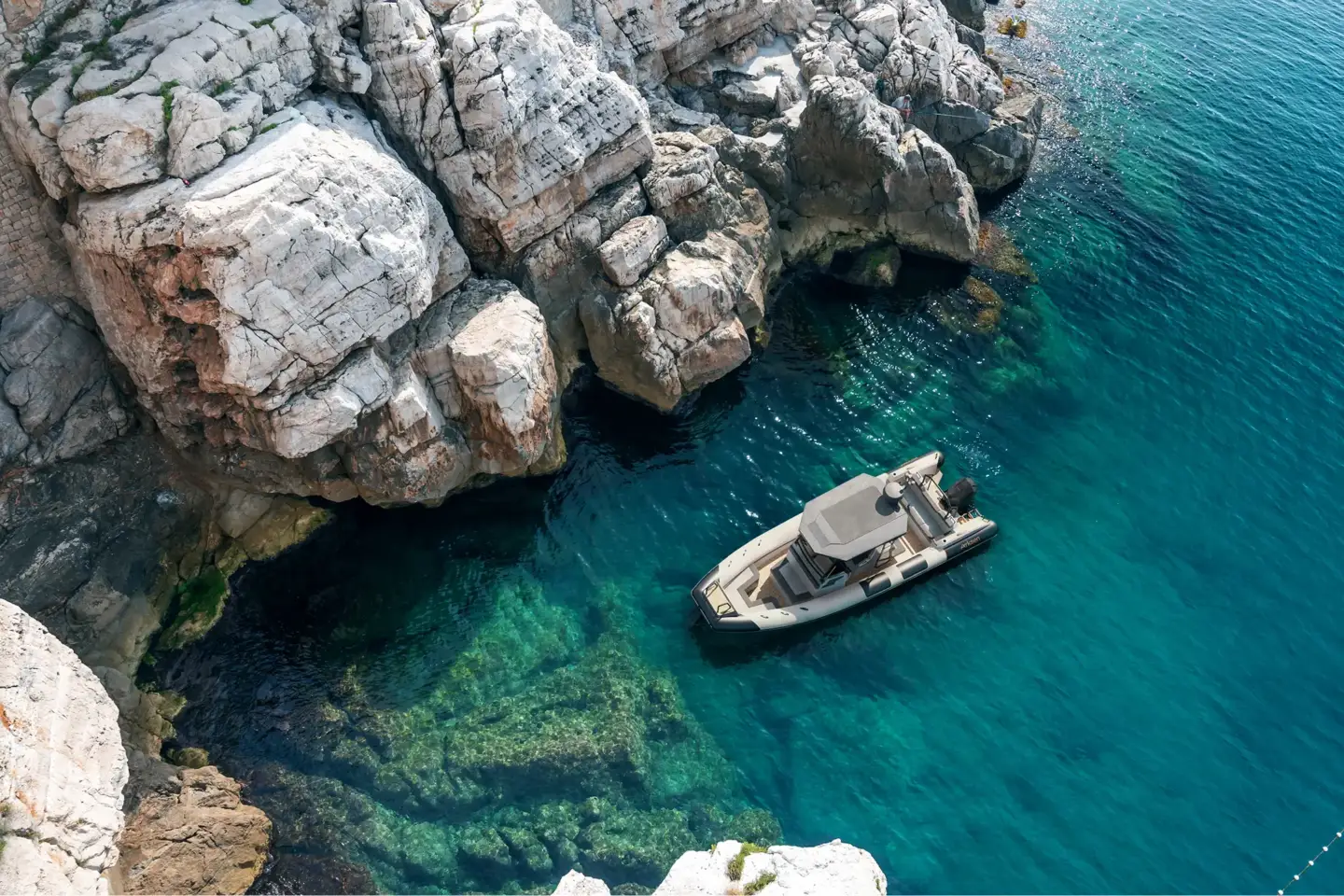 Top Yacht Rendering Studios — Best Yacht Visualization & 3D Renders Compact motor yacht navigating near steep coastal rocks in clear turquoise sea