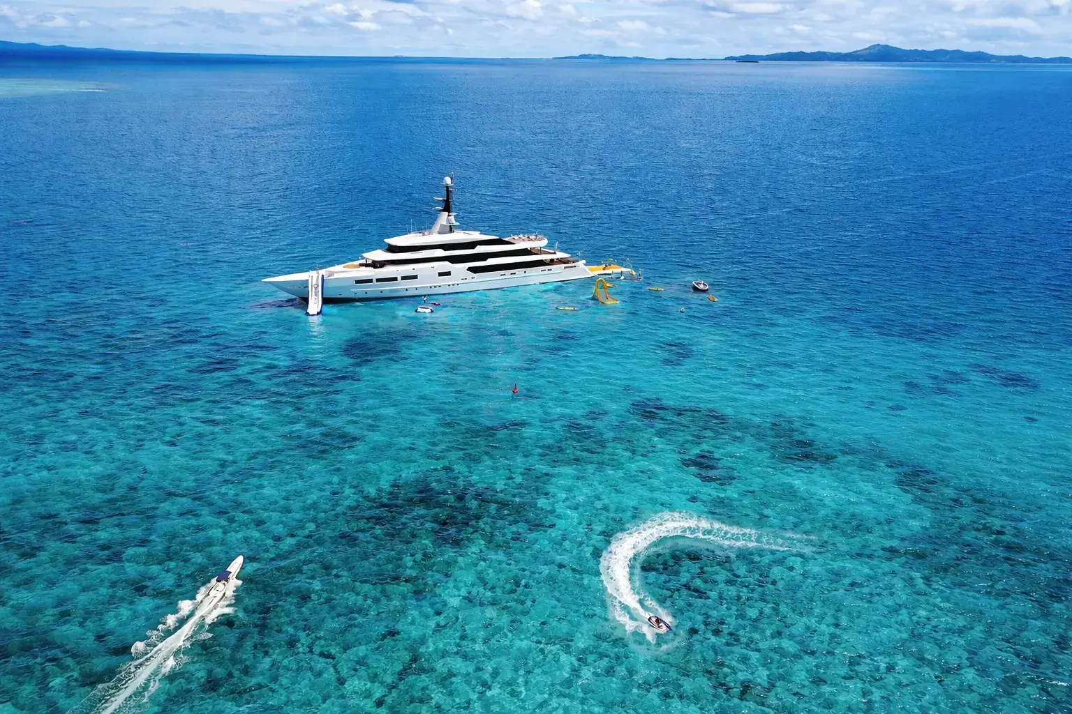 Top Yacht Rendering Studios — Best Yacht Visualization & 3D Renders Large superyacht anchored in shallow tropical water with tenders, swimmers, and water activities