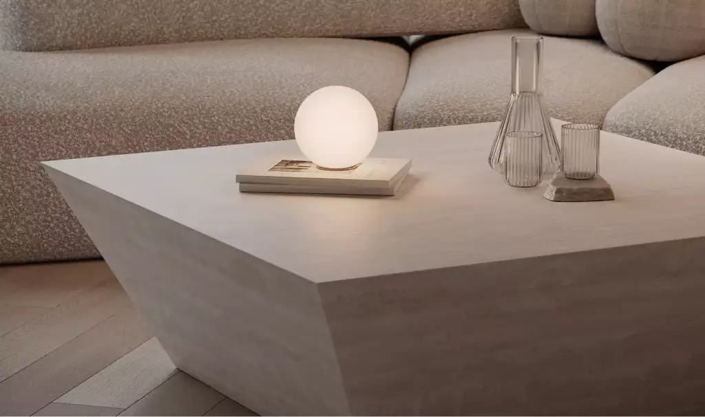 3D furniture rendering of low concrete coffee table with glowing sphere lamp, glass vase, and sofa in modern living room