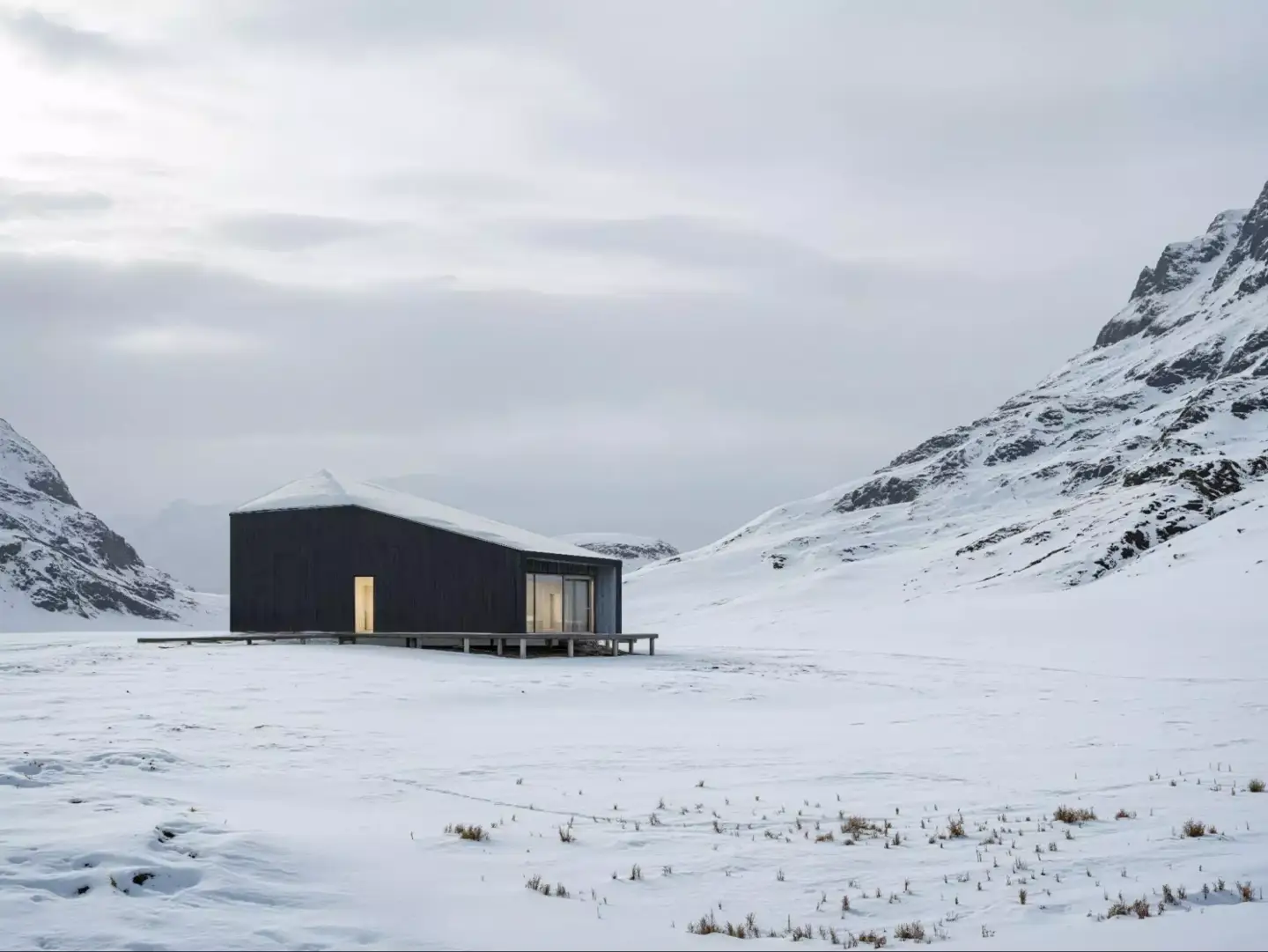 What Is Green Architecture? Meaning, Principles, and Examples Minimal dark cabin in a snowy mountain valley with glowing windows
