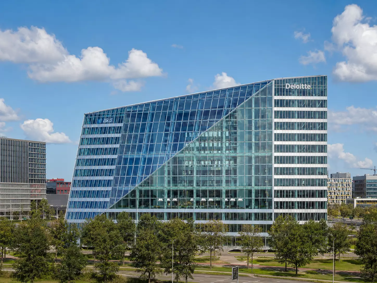 What Is Green Architecture? Meaning, Principles, and Examples Glass office building with trees and reflective facade under a bright blue sky