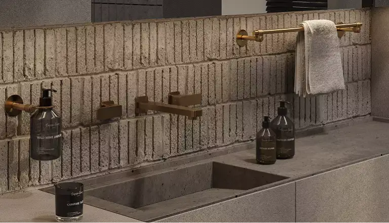 Interior modular homes bathroom sink with brick backsplash, brass rail, faucet, and bottles