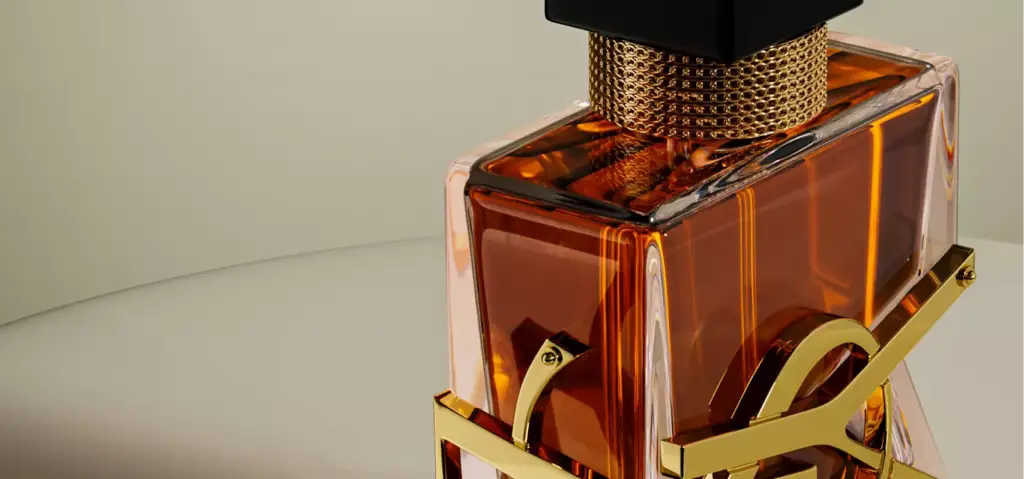 3D cosmetic perfume bottle with amber liquid and gold detail on neutral surface close view