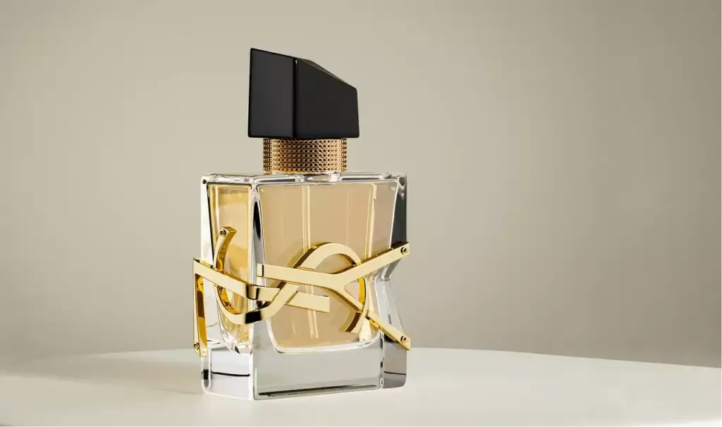 3D cosmetic perfume bottle centered on round pedestal with gold detail and neutral backdrop