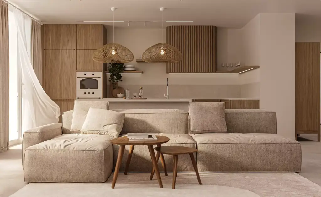 Living room in apartment interior with beige sectional sofa, wood tables, and open kitchen