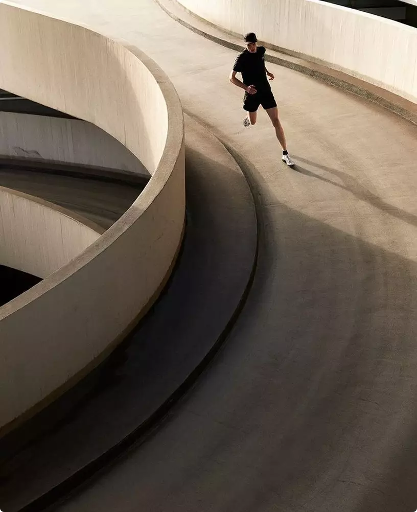 Runner on curved ramp fitness center interior design with smooth concrete architecture and dynamic motion