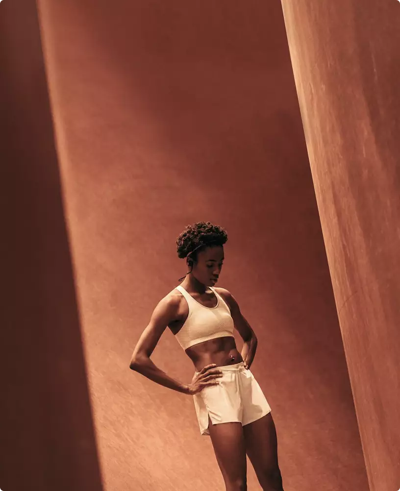 Woman standing in workout outfit fitness center interior design with warm tones and minimal background