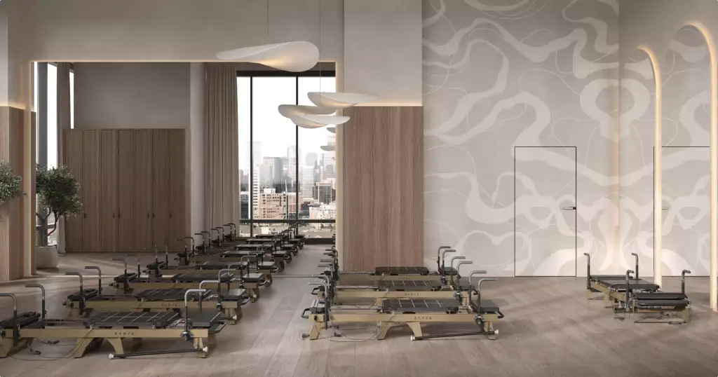 Pilates studio fitness club interior design with reformer machines, mirrors, wood panels, and large window