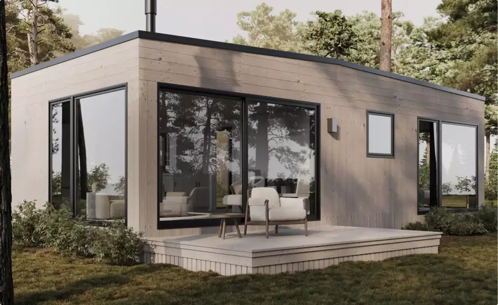 Modern forest house exterior with wood siding, large glass doors, and patio seating in wooded setting