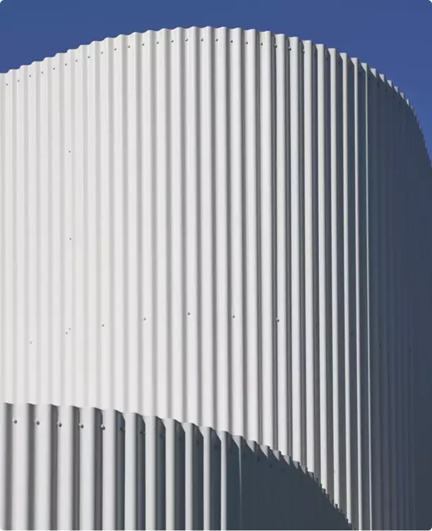 Industrial 3D rendering close up of curved metal facade with vertical ribs against blue sky