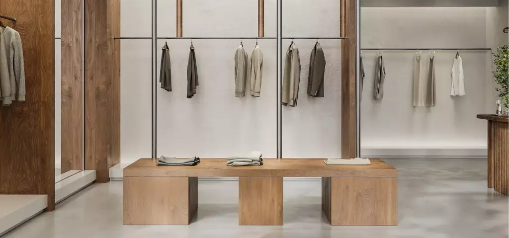 Retail store 3D rendering with central wooden table, spaced clothing racks, and clean modern layout