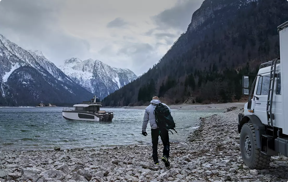 Yacht Rendering of small boat on mountain lake with hiker, rocky shore, truck, and snowy peaks