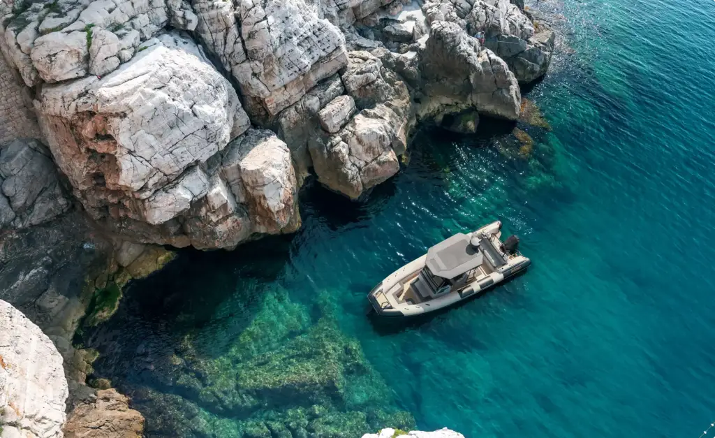 Tender boat near rocky coast in yacht rendering portfolio with clear turquoise water