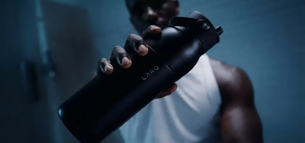 CGI campaign visuals for LARQ black sports bottle held in dramatic blue fitness lighting