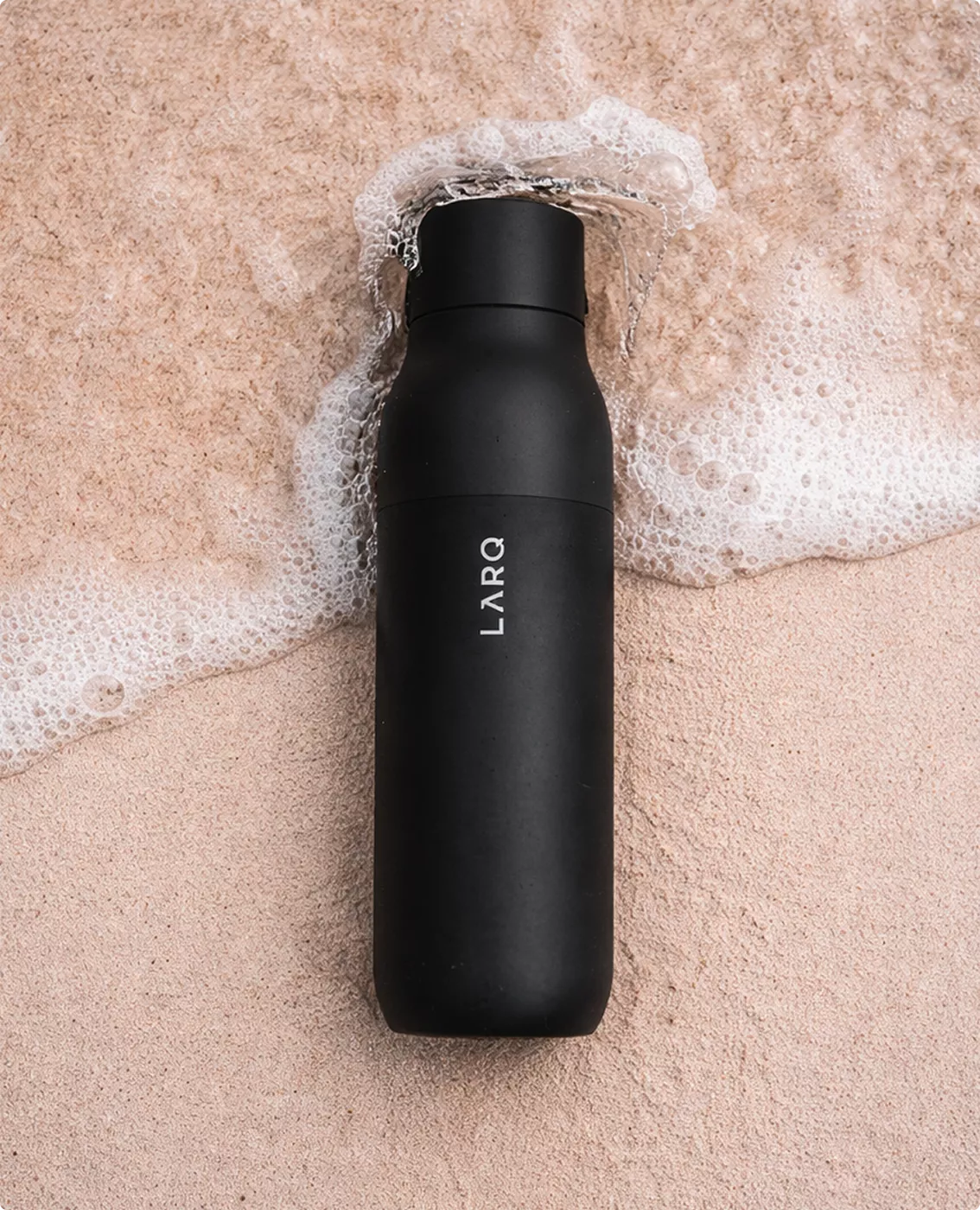 Black LARQ bottle visualization on textured surface with soap bubbles around the reusable bottle