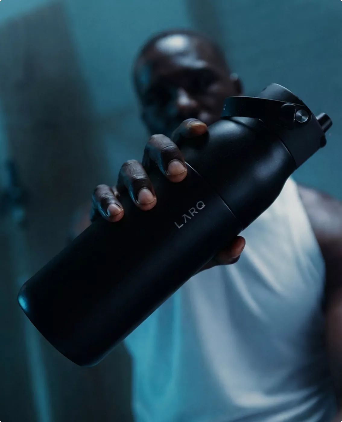 Black LARQ bottle visualization held in hand with dark athletic indoor lighting