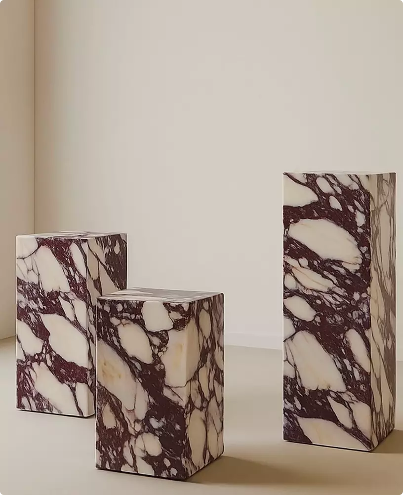 Sculptural marble display blocks designed for luxury beauty retail environments with artistic stone patterns and minimalist styling.