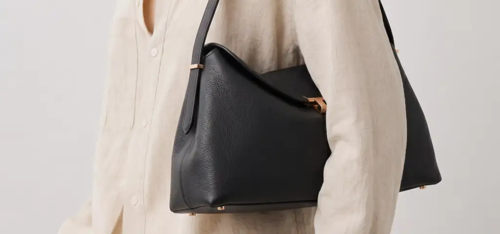 Black Toteme handbag worn with cream outfit and gold hardware detail