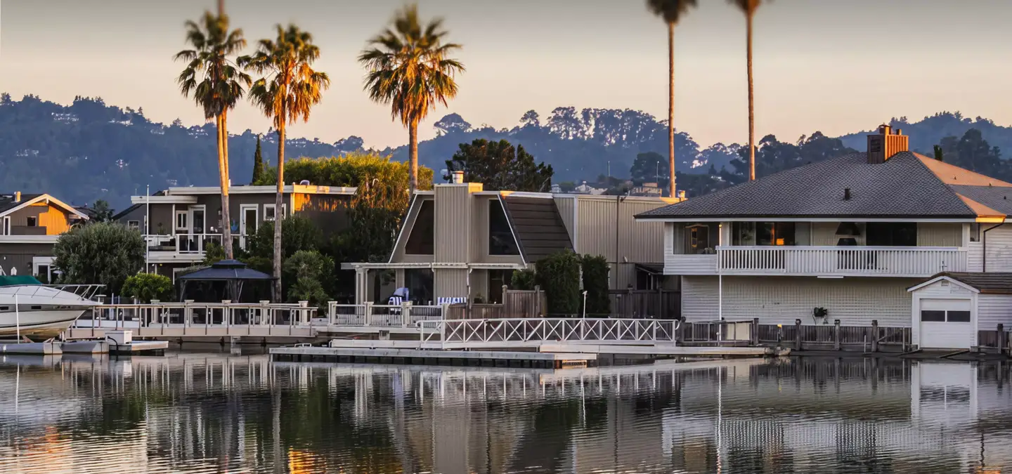 California waterfront homes with docks and palm trees at sunset