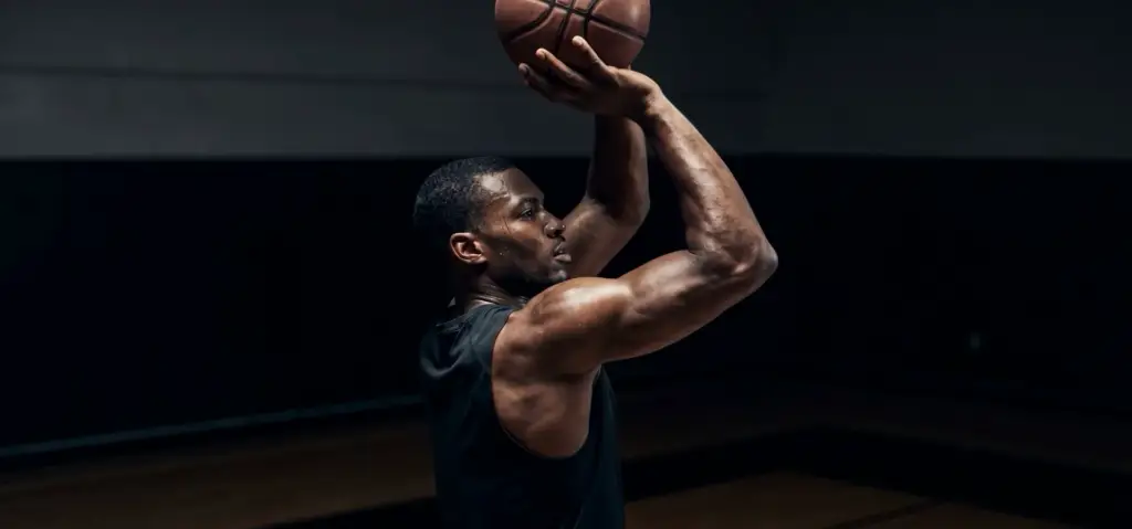 Athlete dunking, dynamic silhouette in a dark studio.