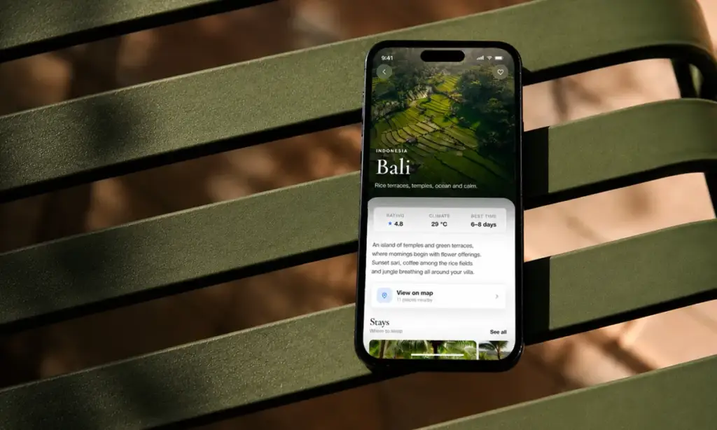 Escape travel app shown on a phone resting on a green bench — Bali destination guide