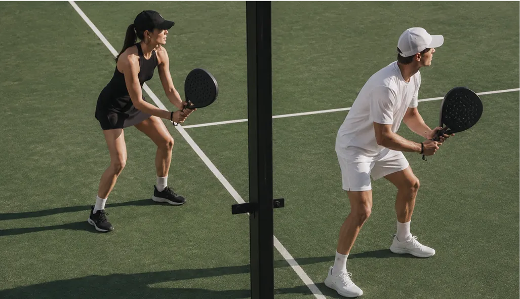 Photorealistic CGI of padel players in a doubles match on the private court, with afternoon palm shadows across the surface.