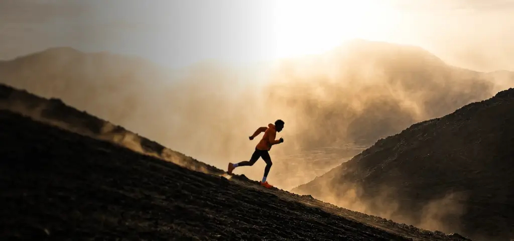 Trail runner sprinting up a mountain at sunset, product launch visualization hero.