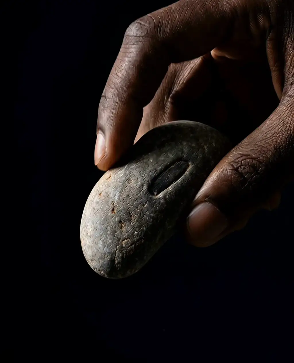 Hand holding a stone on a dark background, concept render.